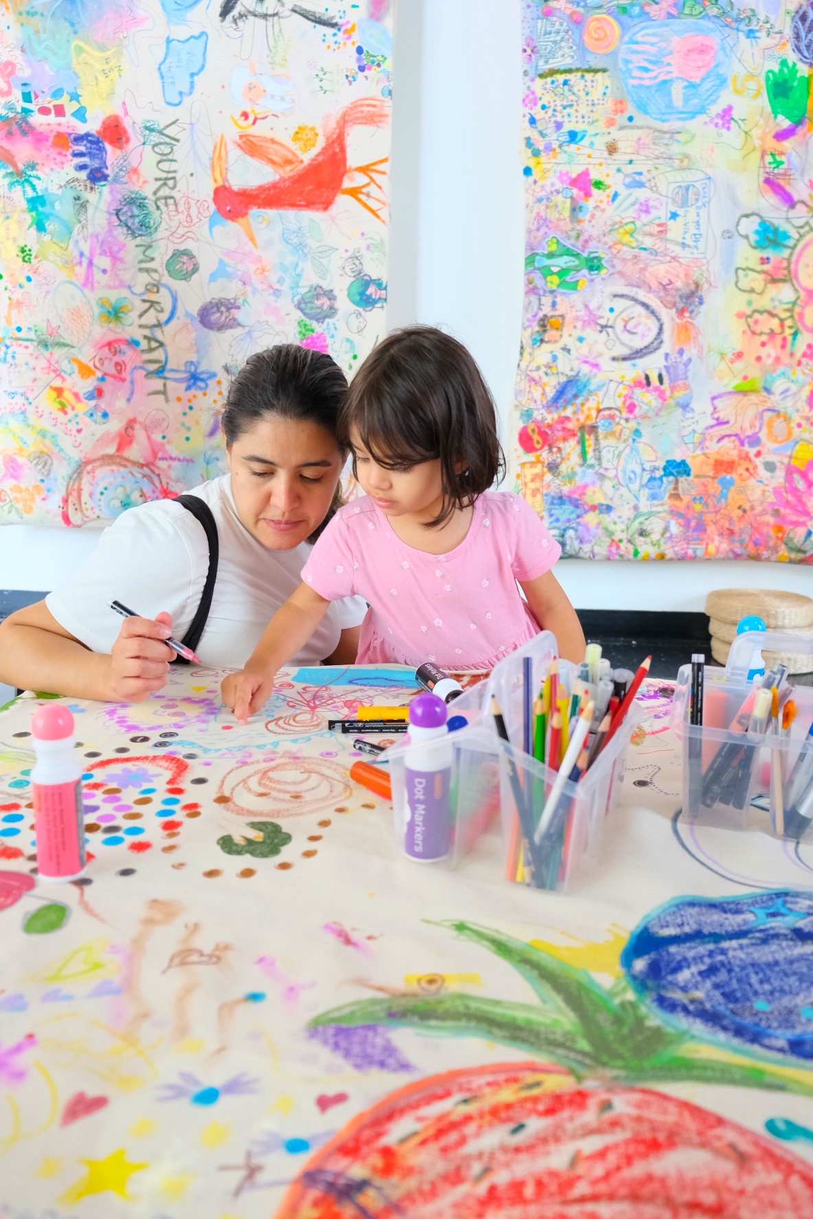An adult and young child draw side by side at the collaborative canvas.