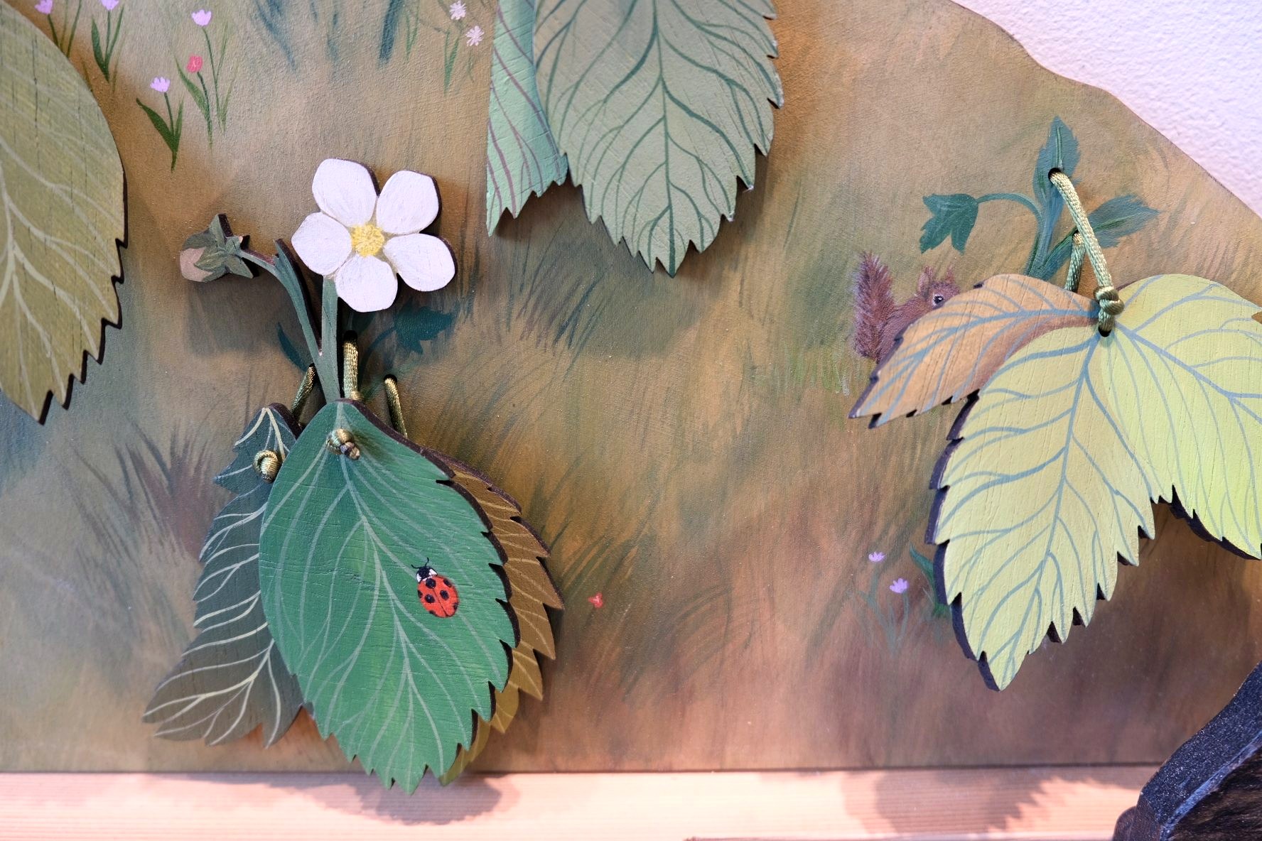 Layered painted leaves with a ladybug and a squirrel peeking through the strawberry patch.