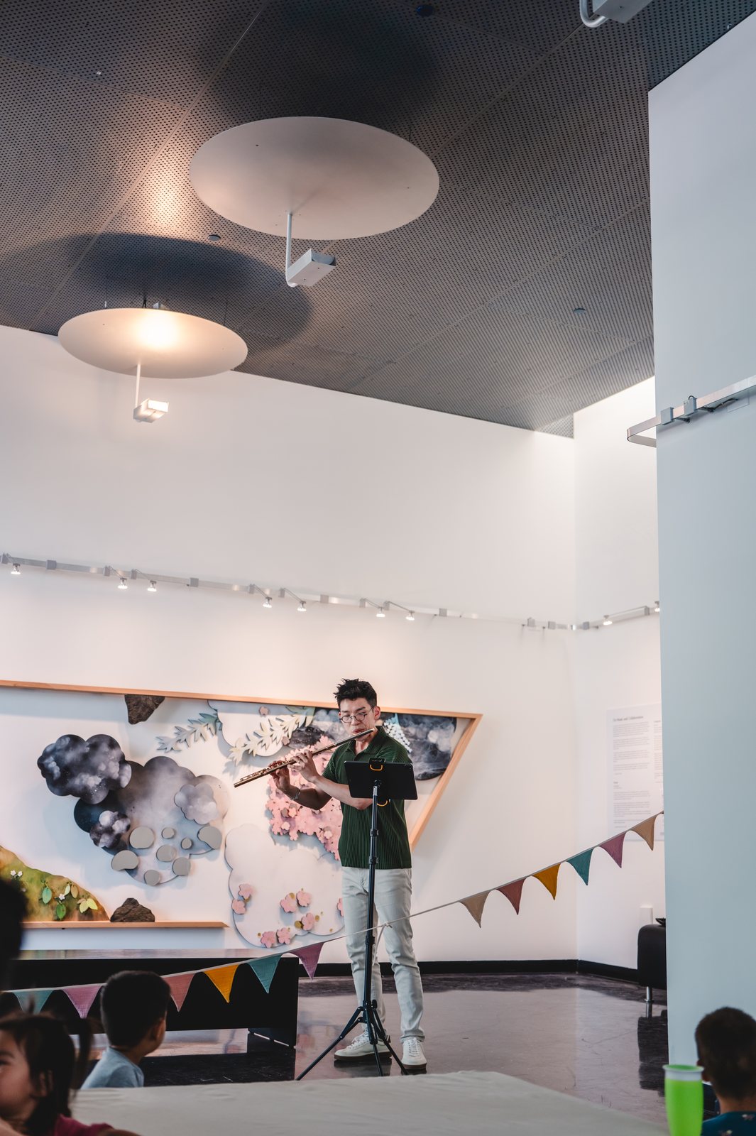 Sungwoo Steven Kim performs flute in front of the Tend the Garden installation.